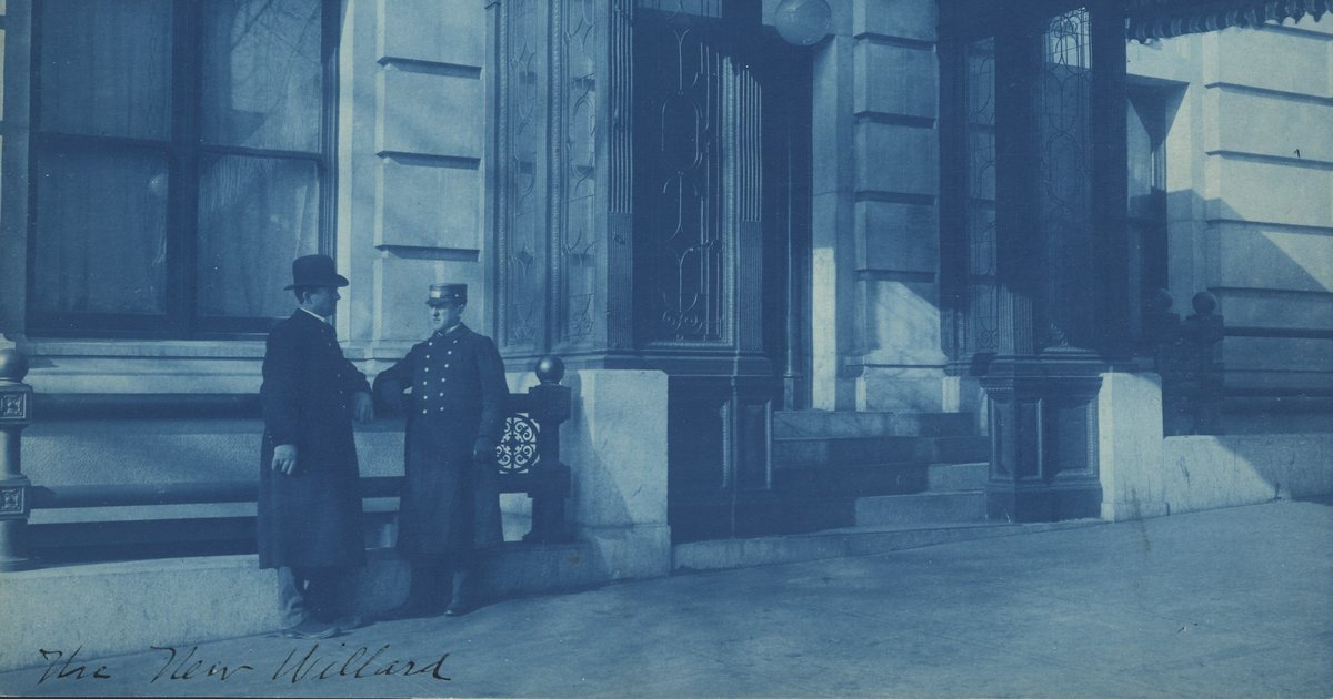A 1901 cyanotype of a uniformed doorman talking with a man in a top hat outside the F Street entrance of the Willard Hotel in Washington.